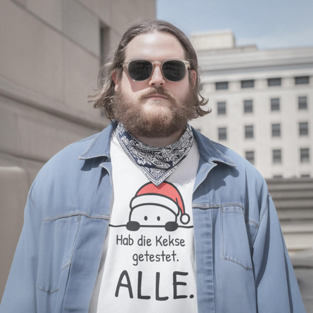 Foto eines übergewichtigen, bärtigen Mannes mit Sonnenbrille und offenem Jeanshemd und darunter weißem Weihnachtsshirt in ruhiger Straßenszene. Auf dem Shirt ist der Aufdruck einer kleinen Weihnachts-Guckfigur mit dem Spruch „Hab die Kekse getestet. ALLE.“